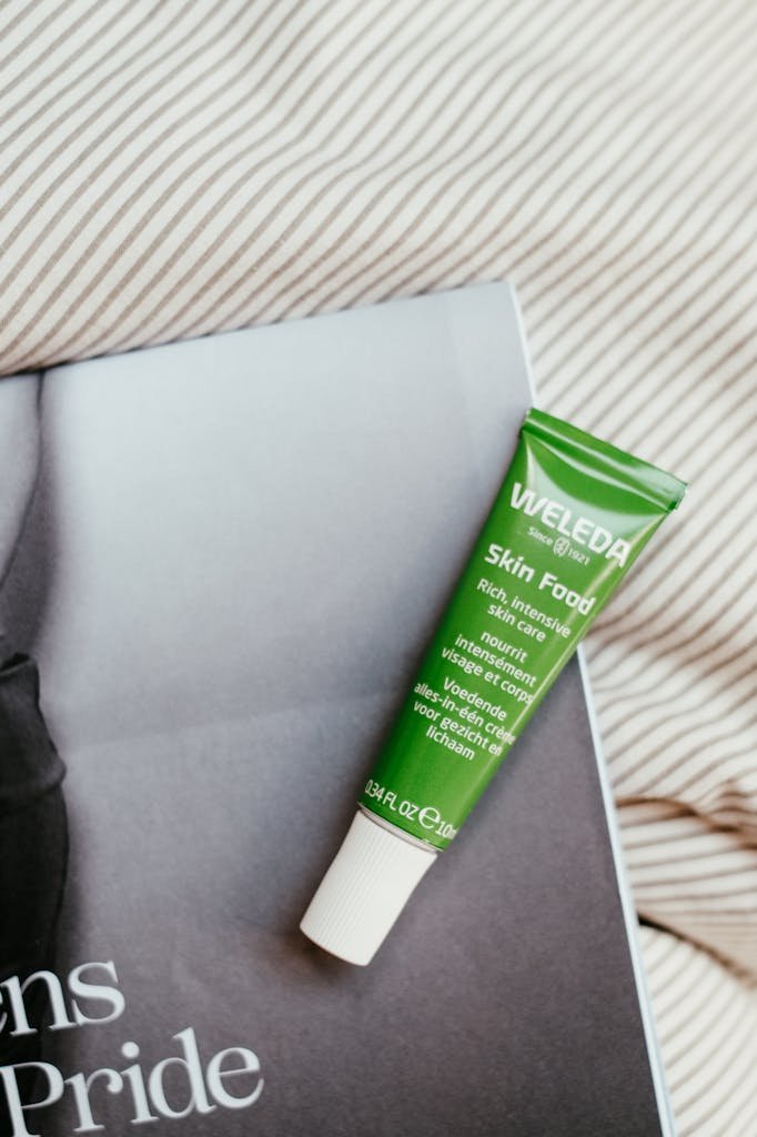 Top view of Weleda Skin Food tube on a magazine against a striped fabric background.